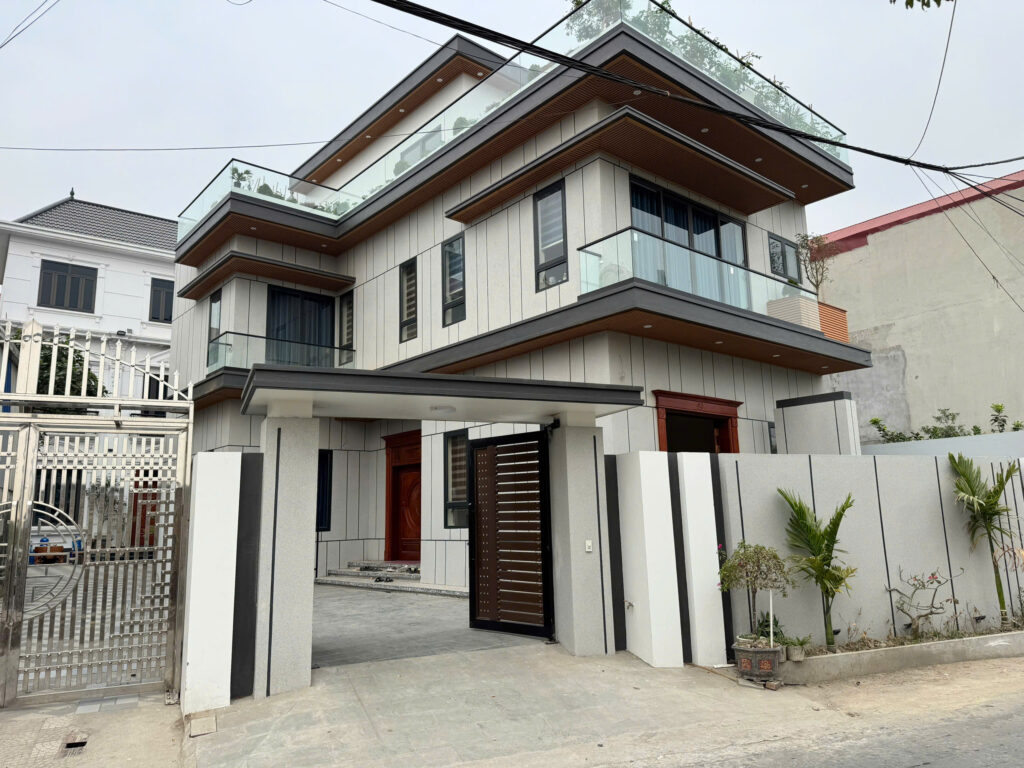 Tổng thể biệt thự Tiên Du với ban công kính, tường sơn đá sáng và đường viền tối