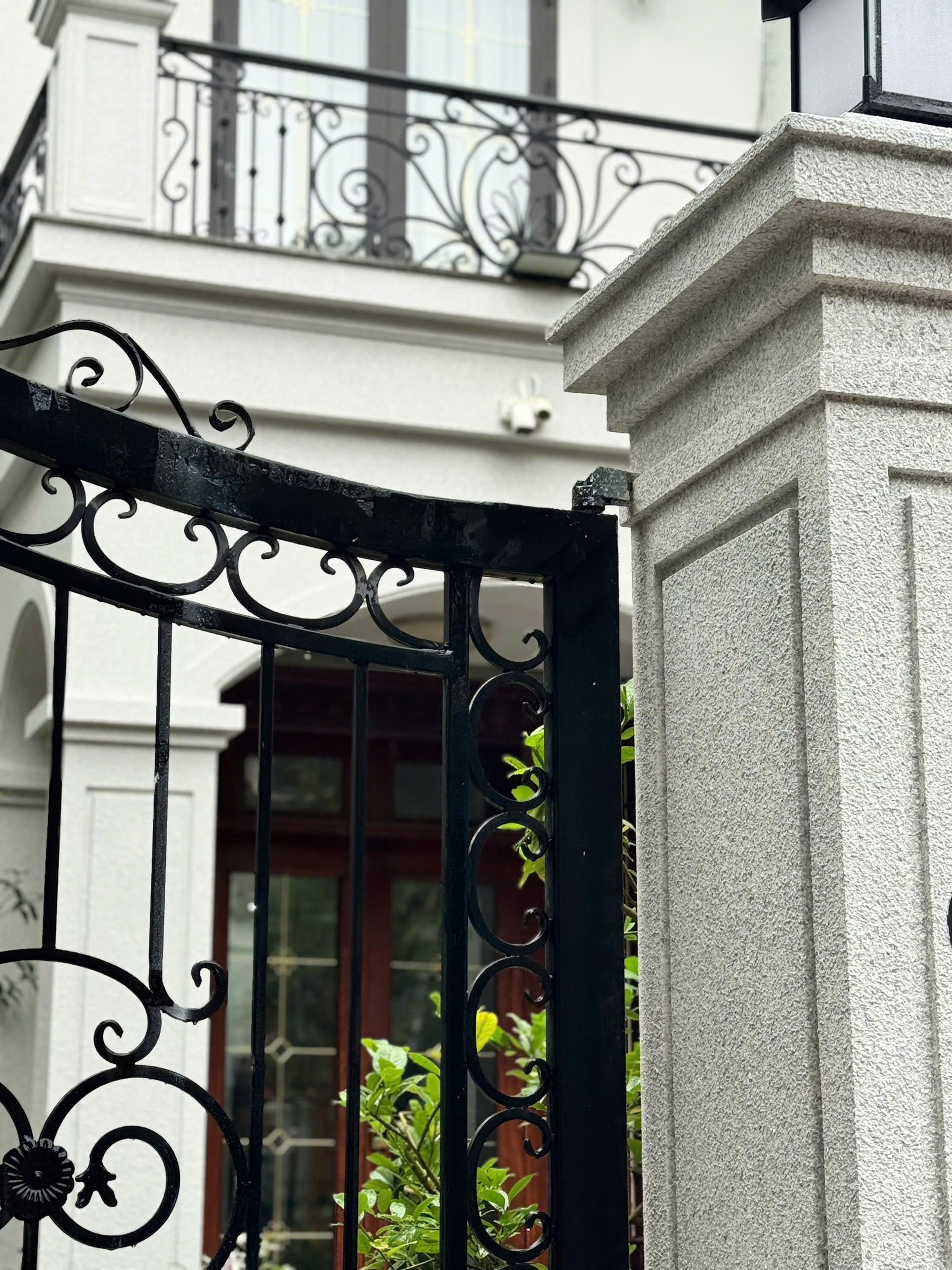 Trụ cổng sơn đá và cánh cổng kim loại tối màu